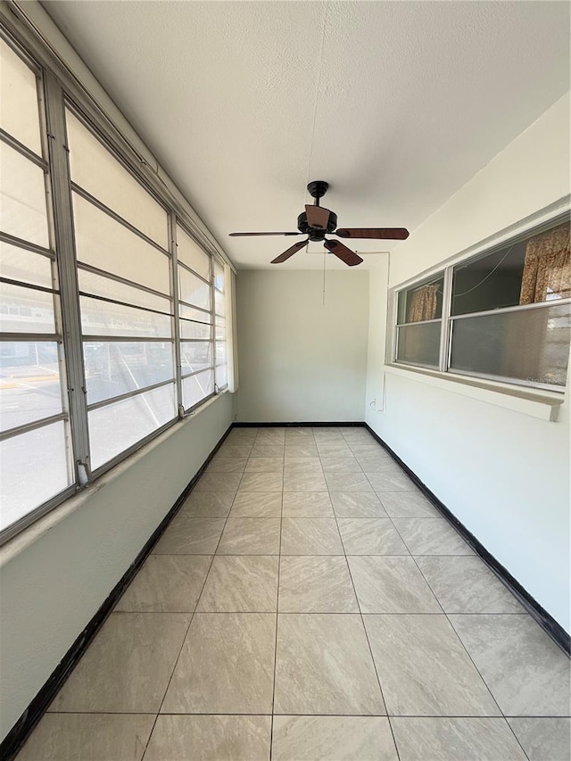 unfurnished sunroom featuring ceiling fan