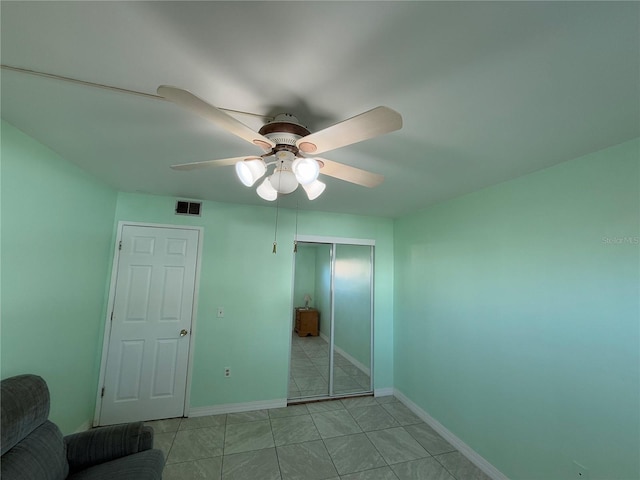 unfurnished bedroom featuring light tile patterned flooring, ceiling fan, and a closet