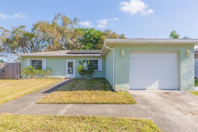 single story home featuring an attached garage, fence, roof mounted solar panels, a front lawn, and stucco siding