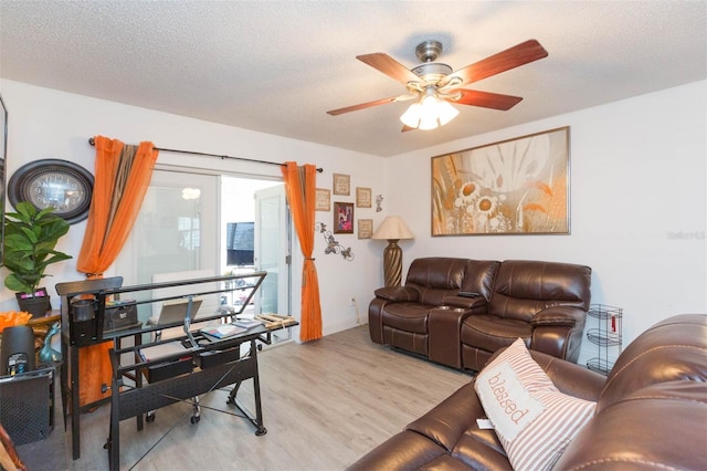 living area with a textured ceiling, ceiling fan, baseboards, and light wood-style floors