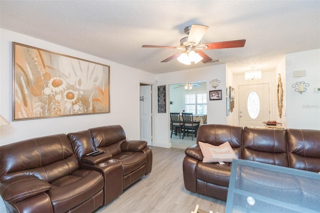 living room featuring light wood-style floors, ceiling fan, and a textured ceiling