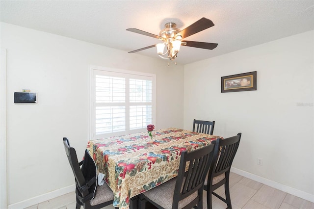 dining area featuring a textured ceiling, ceiling fan, and baseboards