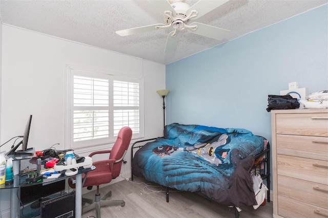 bedroom with a textured ceiling, wood finished floors, and a ceiling fan