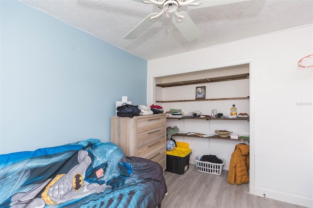 bedroom featuring a textured ceiling, a ceiling fan, and light wood-style floors