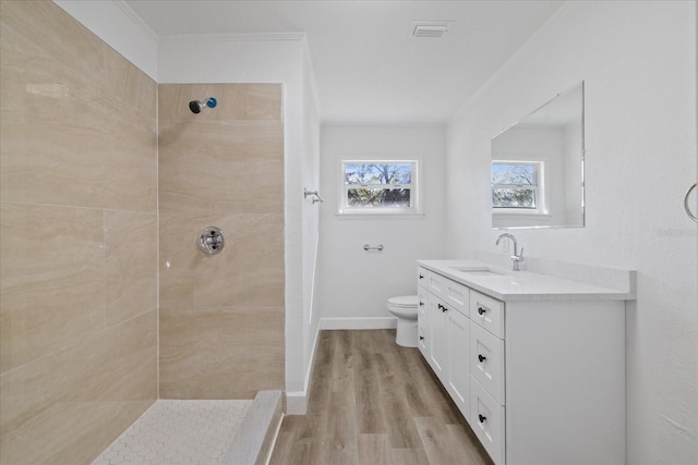 bathroom with vanity, hardwood / wood-style flooring, toilet, and tiled shower