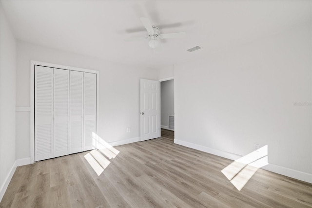 unfurnished bedroom featuring ceiling fan, light wood-type flooring, and a closet