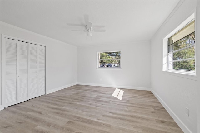 unfurnished bedroom featuring multiple windows, crown molding, light hardwood / wood-style floors, and a closet