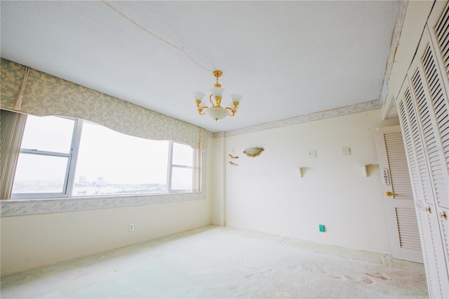 carpeted spare room with a chandelier