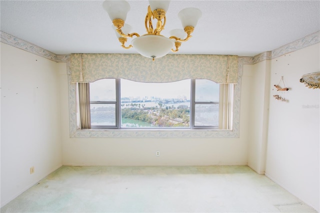 unfurnished room featuring a wealth of natural light, a chandelier, and carpet