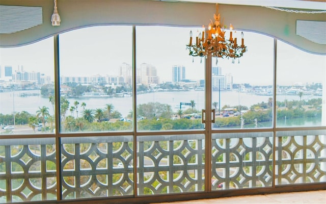 unfurnished sunroom featuring a notable chandelier and a water view