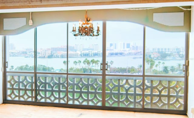 sunroom / solarium with a water view and a notable chandelier