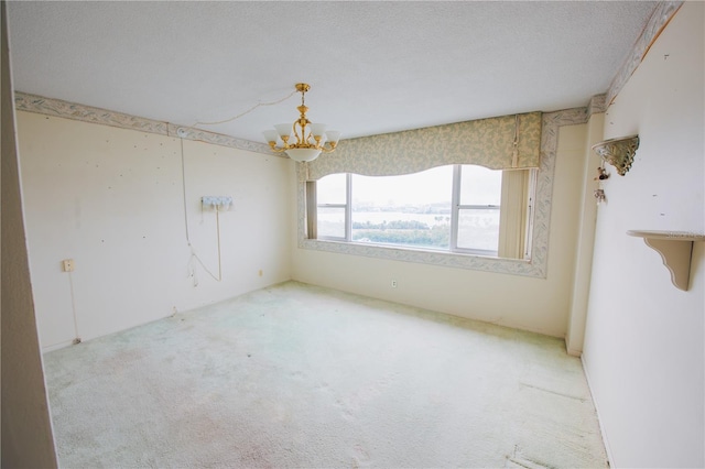 carpeted empty room with an inviting chandelier and a textured ceiling