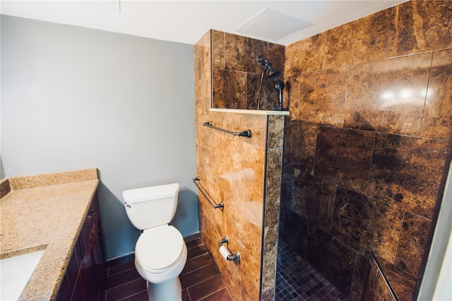 bathroom featuring a tile shower, vanity, and toilet