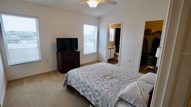 bedroom with vaulted ceiling, connected bathroom, a walk in closet, light colored carpet, and a closet