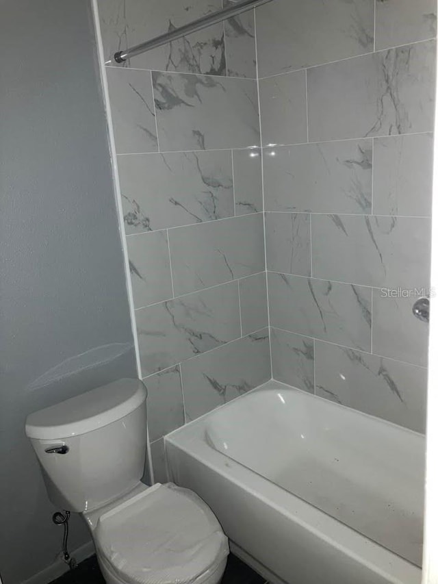 bathroom with tiled shower / bath combo and toilet