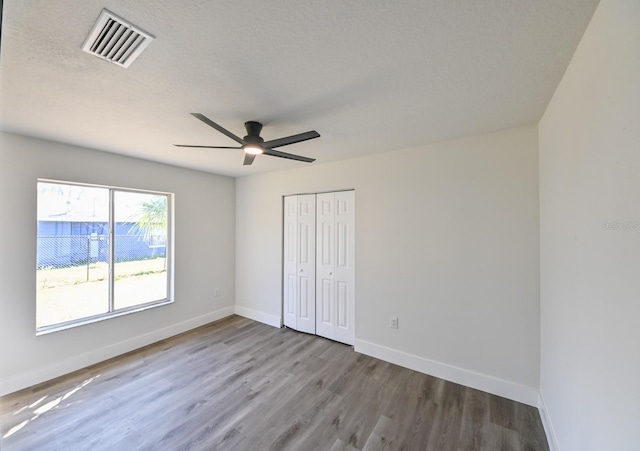 unfurnished bedroom featuring ceiling fan, a textured ceiling, a closet, and light wood-type flooring