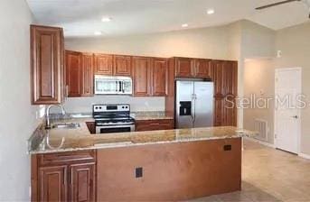 kitchen with lofted ceiling, sink, kitchen peninsula, ceiling fan, and stainless steel appliances