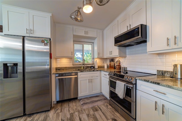 kitchen featuring appliances with stainless steel finishes, dark stone countertops, and white cabinets