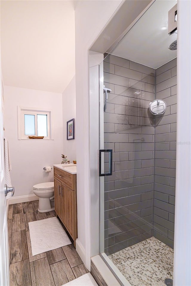 bathroom featuring a shower with door, vanity, and toilet