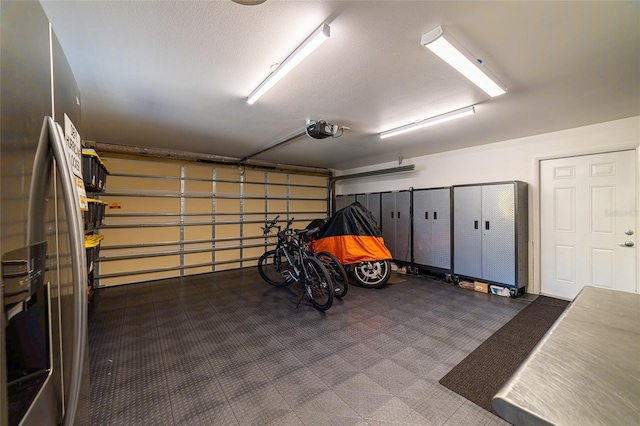 garage with a garage door opener and stainless steel fridge