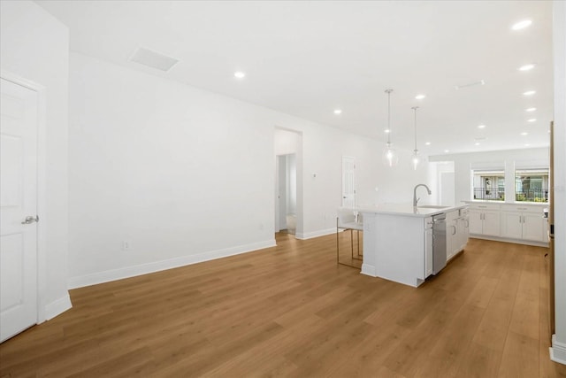 kitchen with sink, a breakfast bar area, white cabinets, stainless steel dishwasher, and a center island with sink