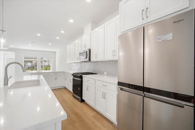 kitchen with decorative light fixtures, sink, white cabinets, backsplash, and stainless steel appliances