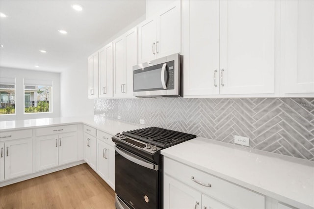 kitchen with tasteful backsplash, white cabinetry, appliances with stainless steel finishes, and light hardwood / wood-style floors