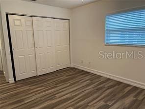 unfurnished bedroom with dark hardwood / wood-style floors and a closet