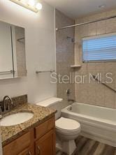 full bathroom with vanity, hardwood / wood-style floors, toilet, and tiled shower / bath