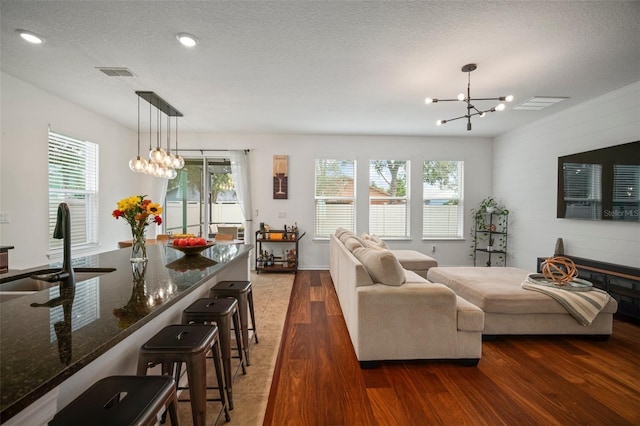 living room with dark wood-type flooring, a wealth of natural light, sink, and a notable chandelier