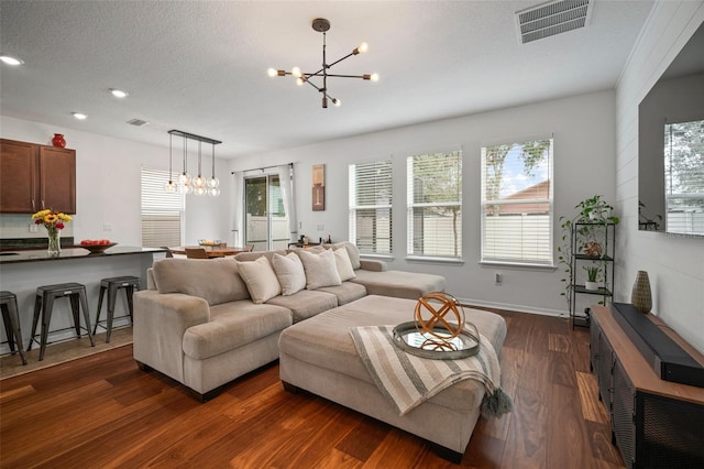 living room with an inviting chandelier, dark hardwood / wood-style flooring, and a textured ceiling