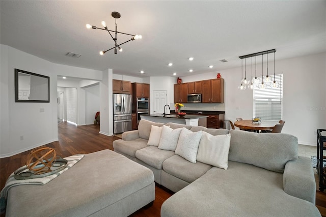 living room featuring an inviting chandelier, dark hardwood / wood-style flooring, and sink