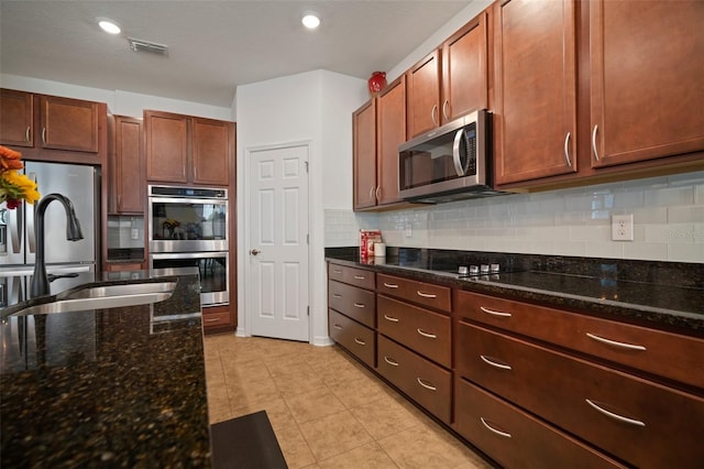 kitchen featuring sink, backsplash, dark stone counters, light tile patterned floors, and stainless steel appliances