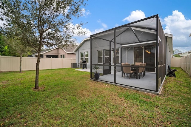 back of property with a lawn, central air condition unit, glass enclosure, and a patio area