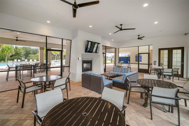 interior space featuring a multi sided fireplace, ceiling fan, and french doors