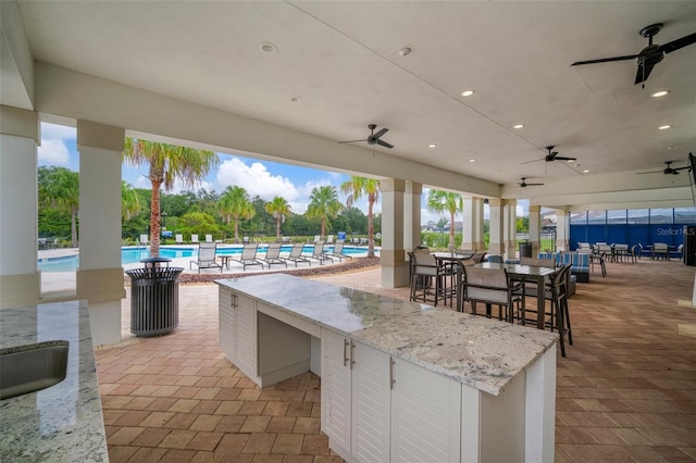 view of patio / terrace with a community pool, an outdoor bar, and ceiling fan