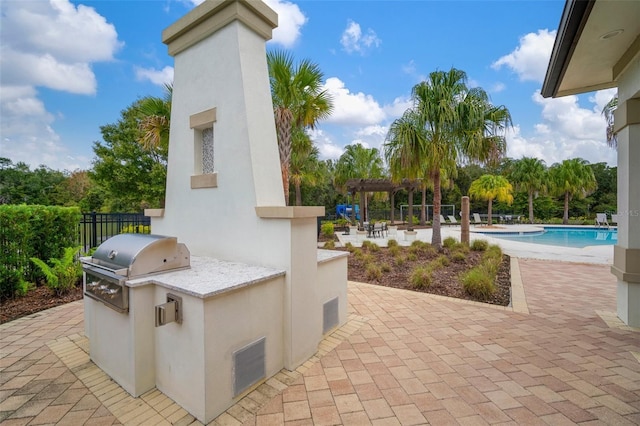 view of patio with exterior kitchen, grilling area, and a pergola