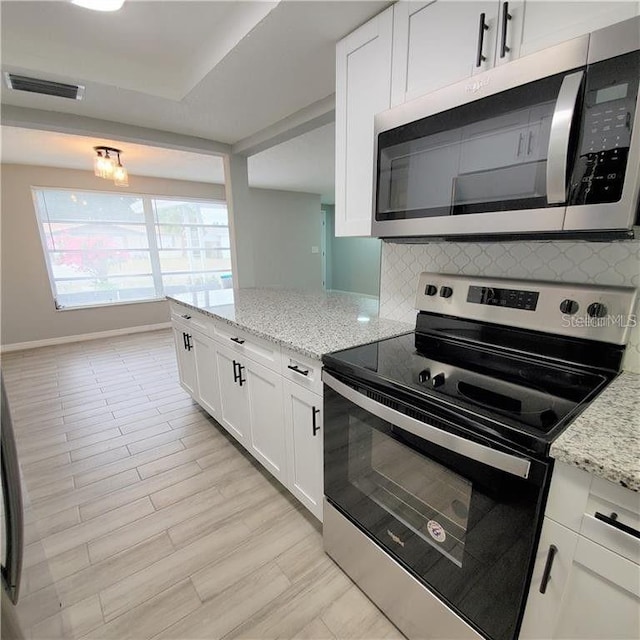 kitchen with white cabinetry, appliances with stainless steel finishes, and light stone countertops