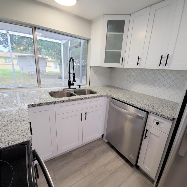 kitchen featuring white cabinetry, stainless steel dishwasher, sink, and light stone counters