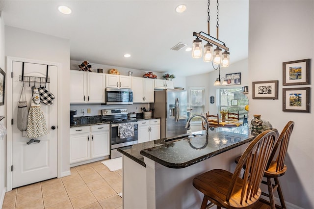 kitchen featuring sink, a breakfast bar, white cabinetry, stainless steel appliances, and decorative light fixtures