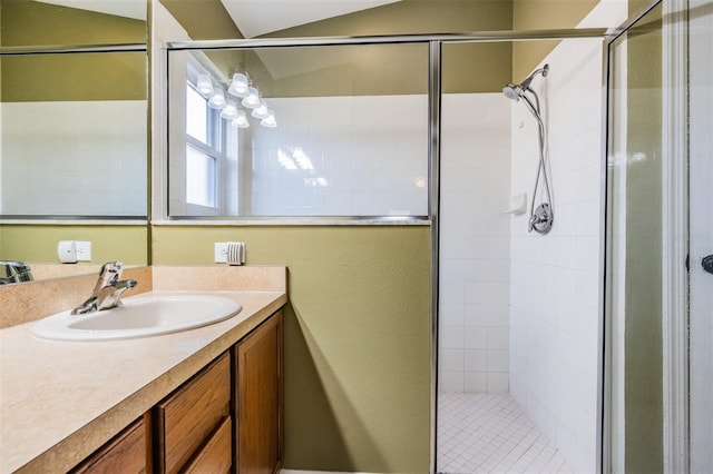 bathroom with tiled shower, vanity, and lofted ceiling