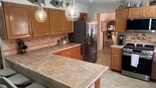 kitchen featuring pendant lighting, backsplash, stainless steel appliances, light tile patterned flooring, and kitchen peninsula