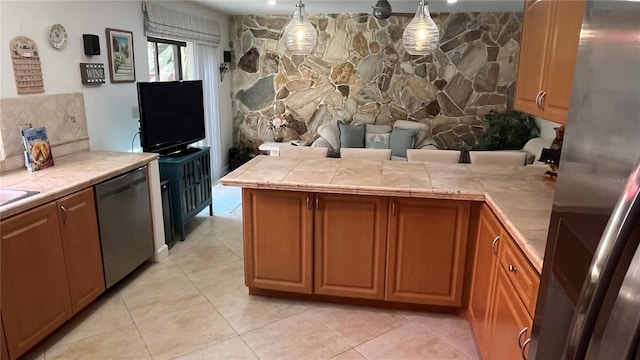 kitchen with pendant lighting, tasteful backsplash, tile counters, light tile patterned floors, and stainless steel appliances