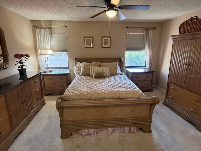 carpeted bedroom with ceiling fan, multiple windows, and a textured ceiling