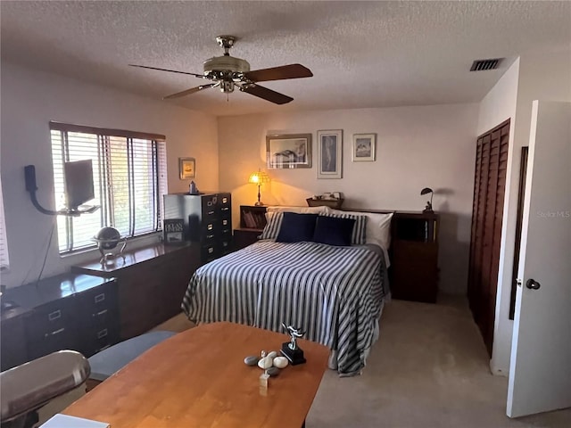 carpeted bedroom featuring ceiling fan and a textured ceiling