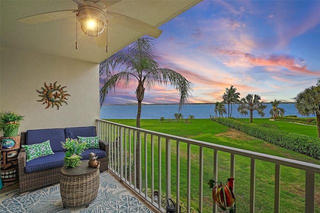 balcony at dusk with ceiling fan and a water view