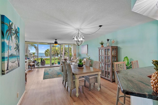 dining space featuring ceiling fan with notable chandelier, light hardwood / wood-style flooring, expansive windows, and a textured ceiling