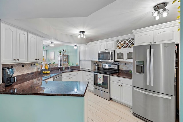 kitchen with backsplash, stainless steel appliances, kitchen peninsula, and white cabinets