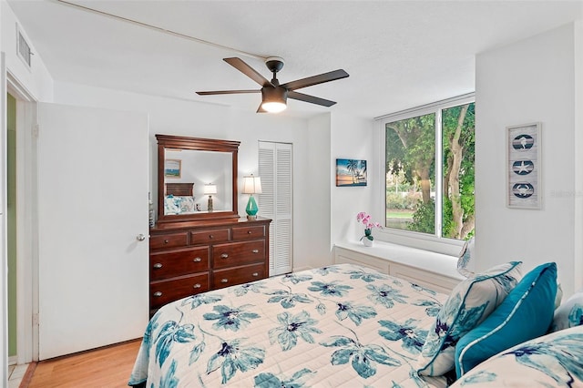 bedroom with light hardwood / wood-style flooring, ceiling fan, and a closet