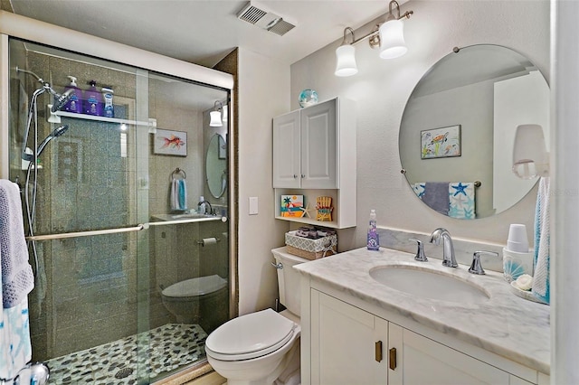 bathroom featuring vanity, a shower with shower door, and toilet